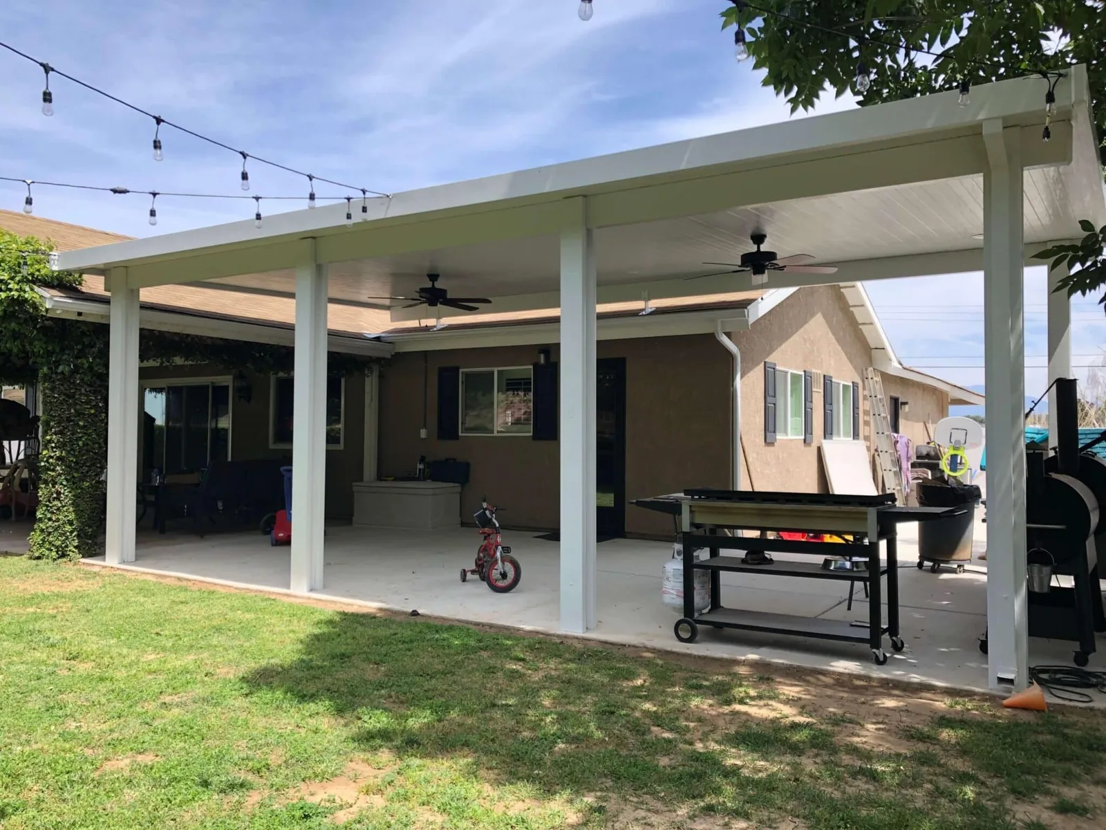 Wide attached patio cover with fans and string lighting