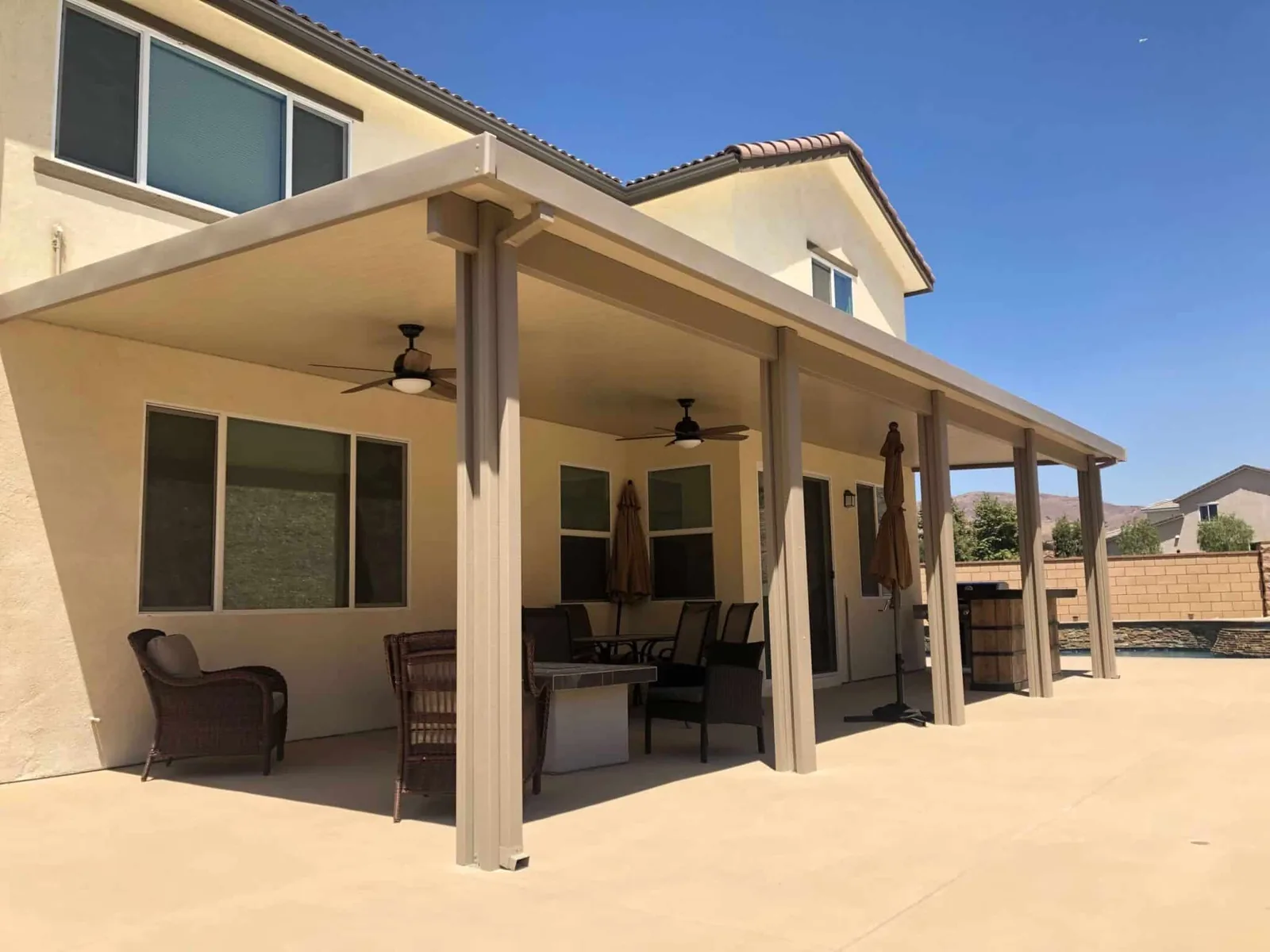 Solid tan patio cover with ceiling fans and lounge seating