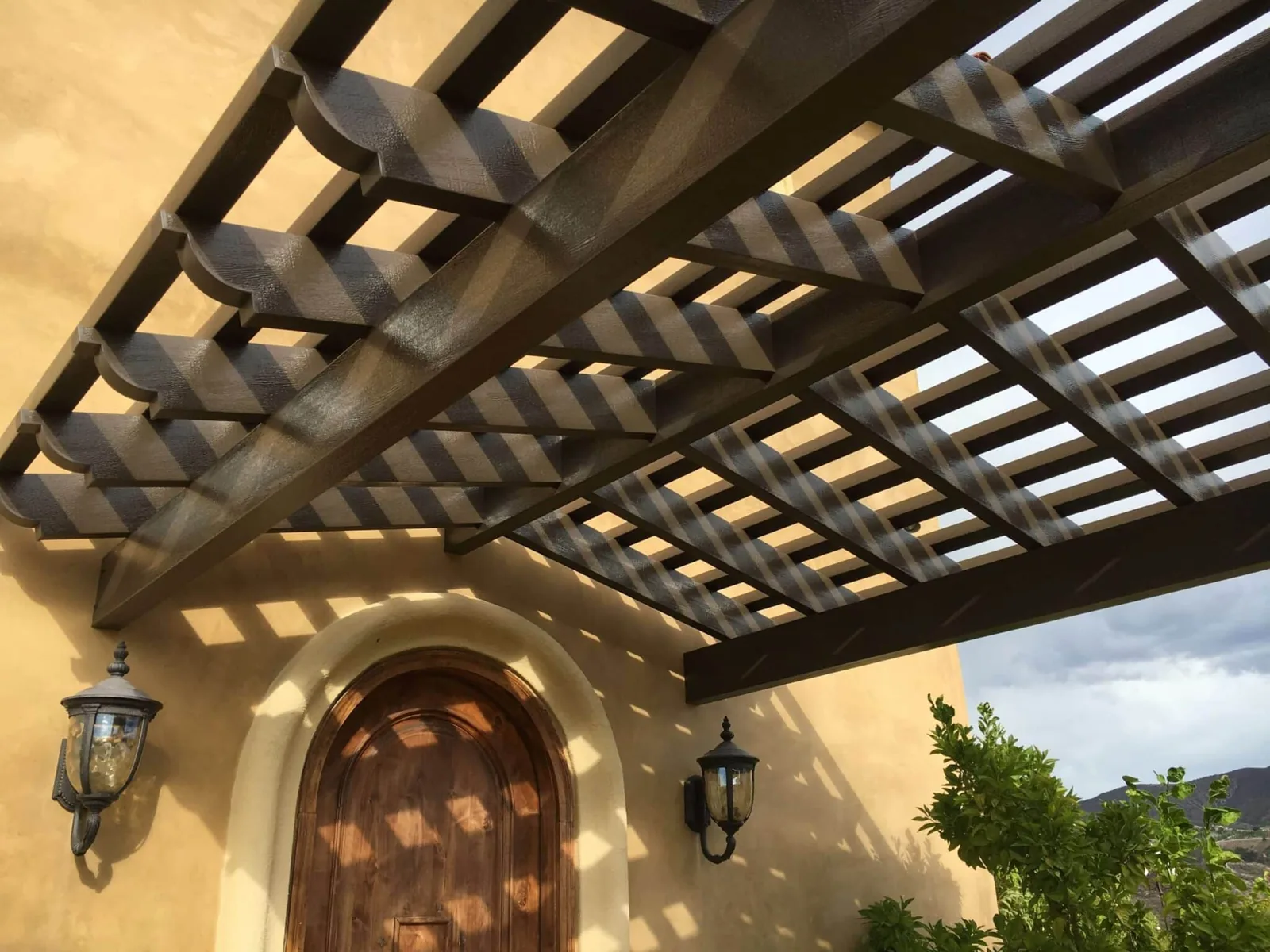 Dark wood-look pergola framing an arched entry