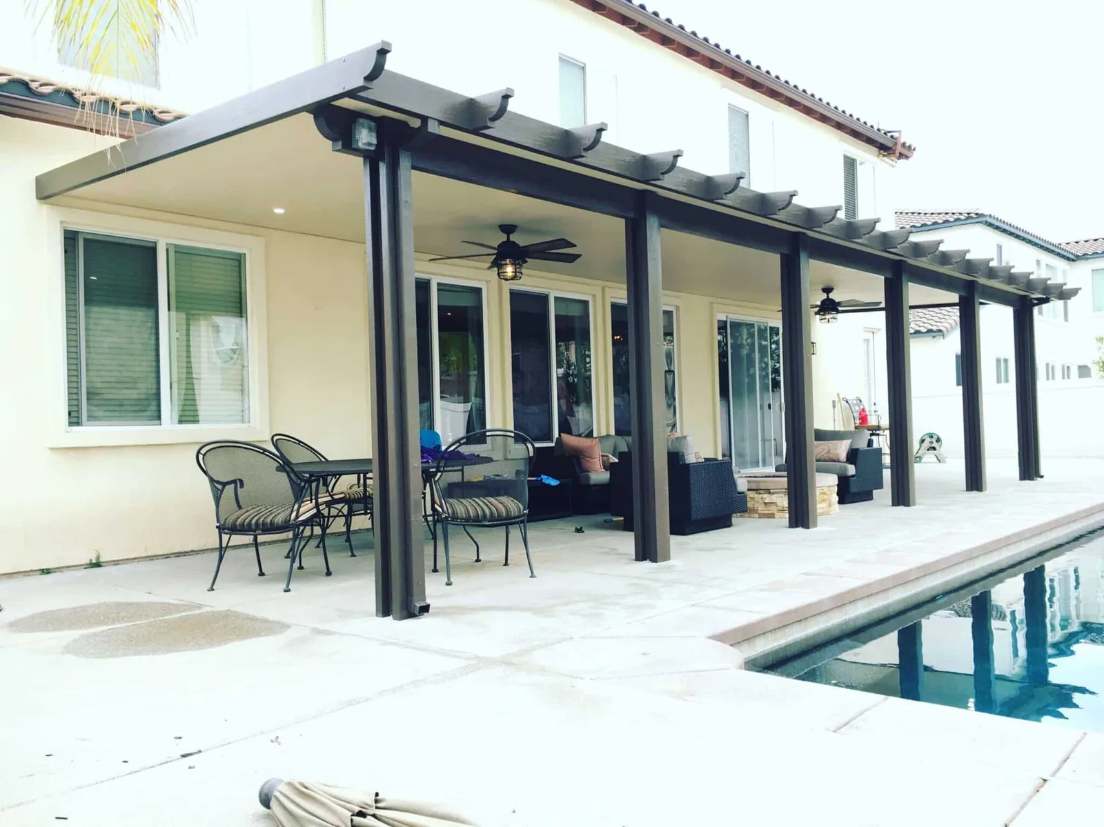 Dark poolside patio cover with fans and recessed lighting