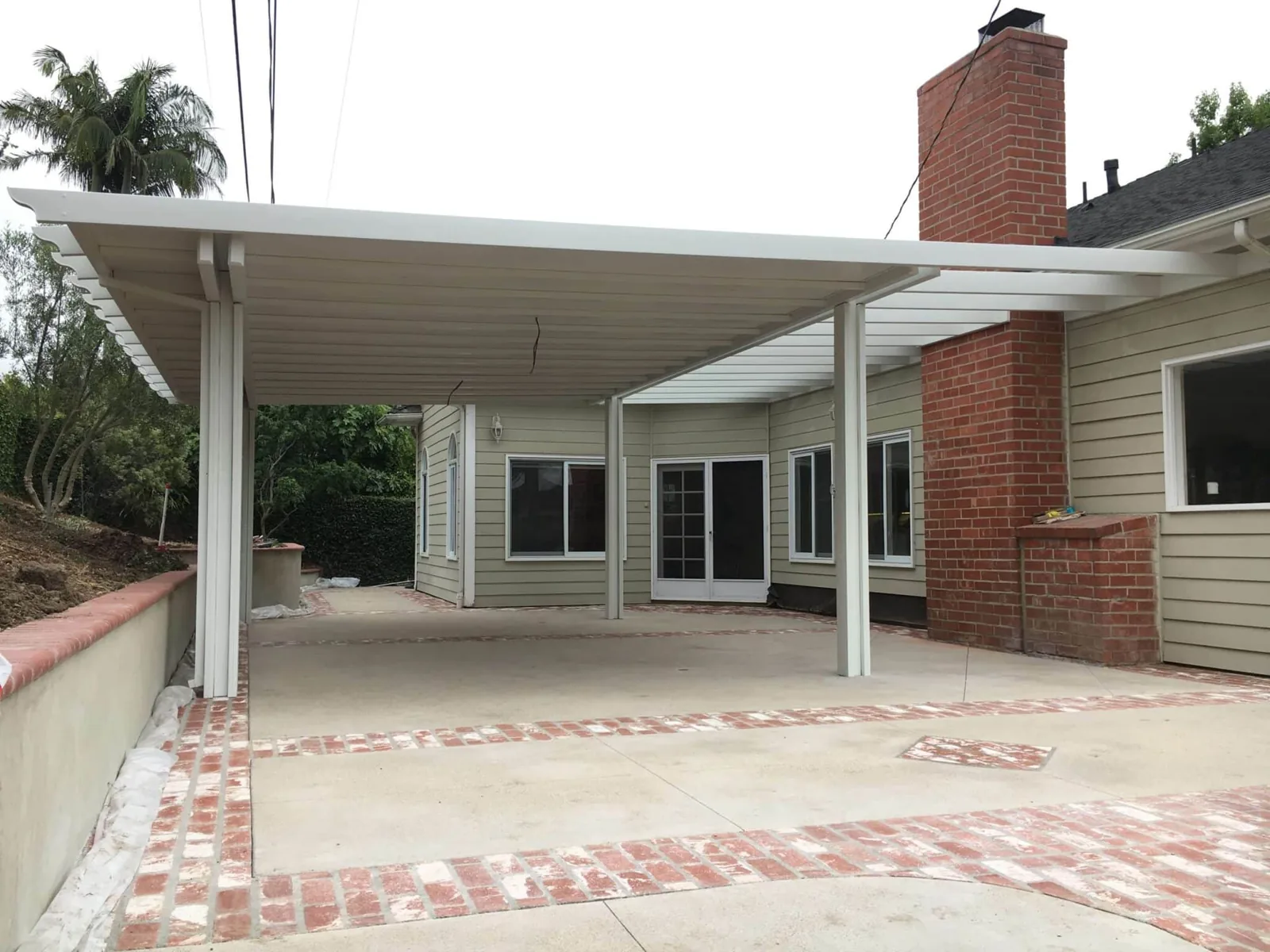White solid patio cover attached to a brick home